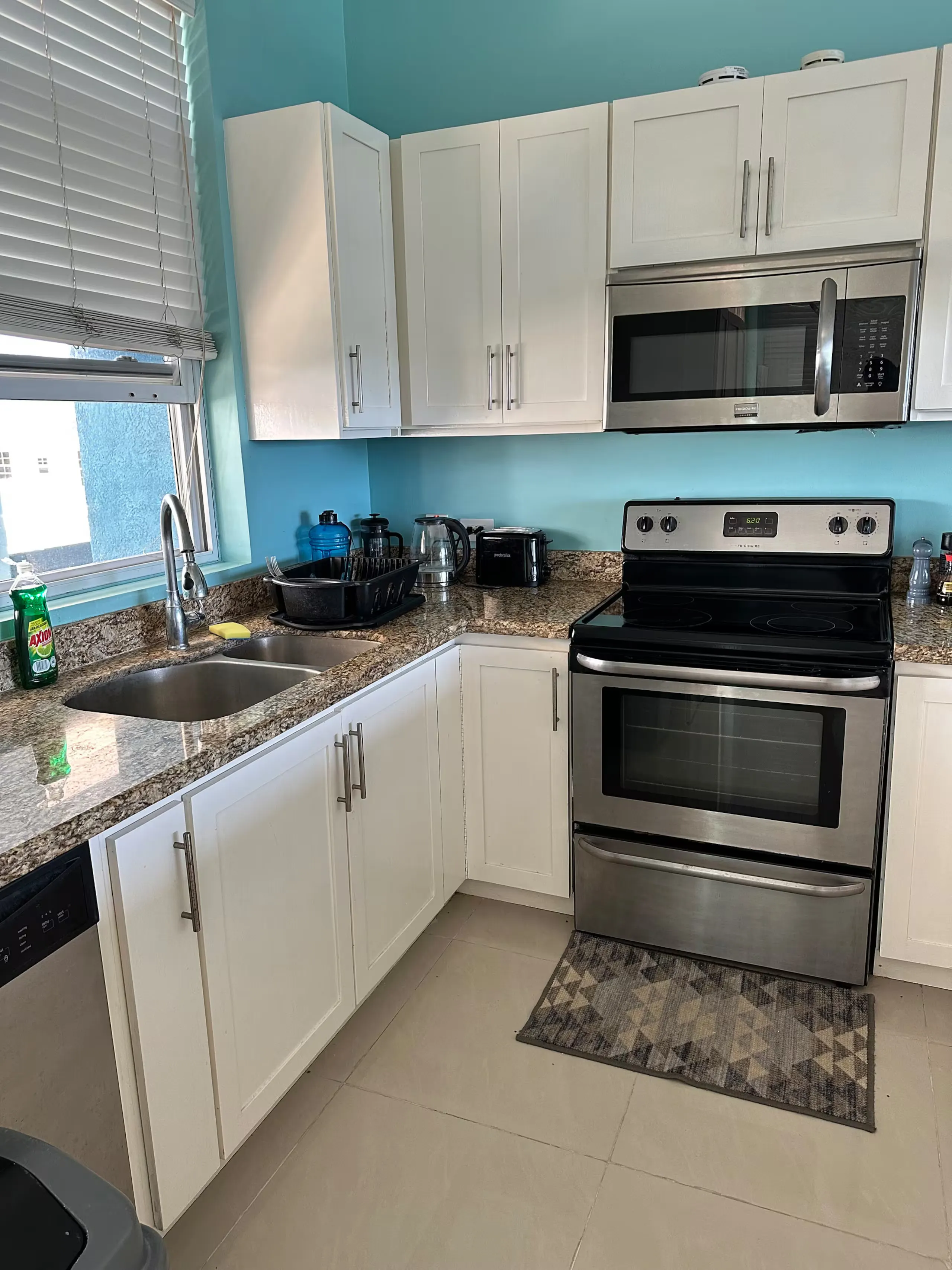 Kitchen with a stainless steel range and microwave, granite counters and white cabinetry.